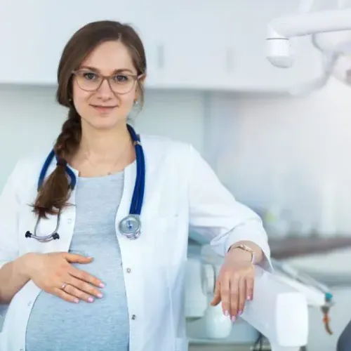 Schwangere medizinische Angestellte steht neben einem behandlungsstuhl