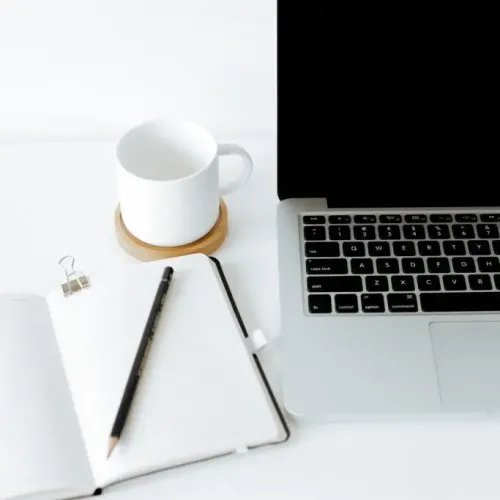 labtop, Notizbuch mit Stift und weiße Kaffeetasse auf einem Schreibtisch
